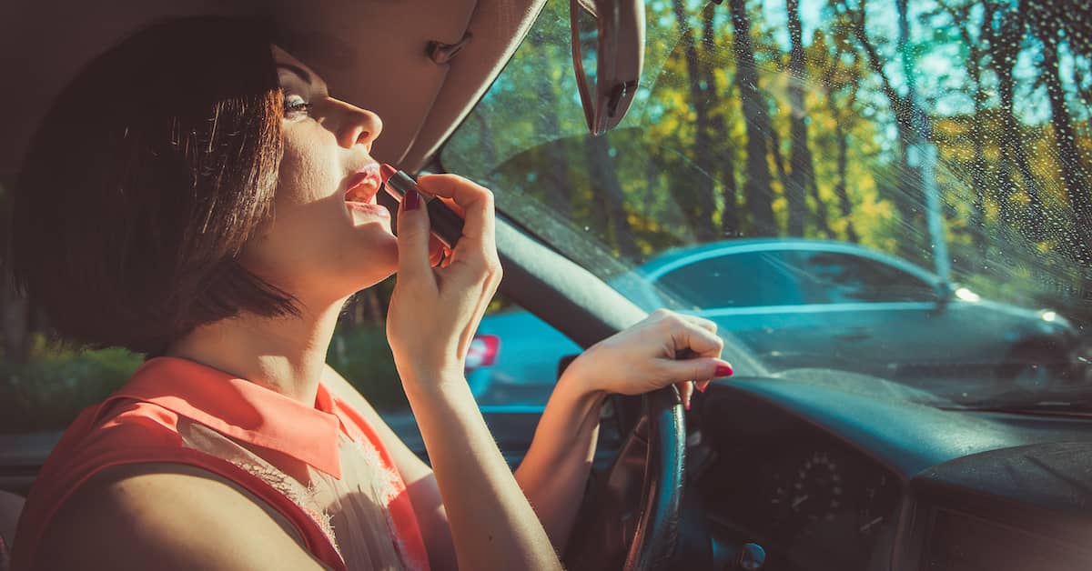 Negligent woman applying lipstick while driving. | Colling Gilbert Wright